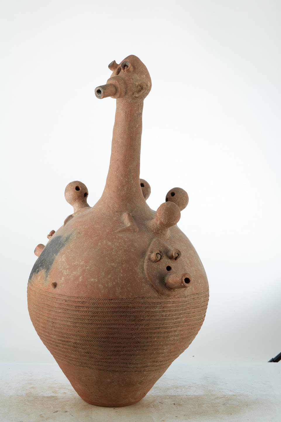 Dogon.(vase), d`afrique : Mali, statuette Dogon.(vase), masque ancien africain Dogon.(vase), art du Mali - Art Africain, collection privées Belgique. Statue africaine de la tribu des Dogon.(vase), provenant du Mali, 1973 Vase BANKONI de cérémonie funéraire en terre cuite .Le vase est ouvert par la base.Il a une H.de 118cm.et un diam.de60cm.Il représente un corps avec un long cou plus la tête 45cm.  Sur le corps 4 petites boules représentant des têtes avec 3 trous  sybolisant  le nez et  deux yeux en plus  deux petits bras.Sous les petites têtes 3 visages plats avec 2 yeux ,un nez et une bouche allongée trouée. pour laisser passer la fumée.Les traits anthropomorphes accompagnaient les hommes dans les rites rythmant leur existance,le lien sacré entre le vivant et l