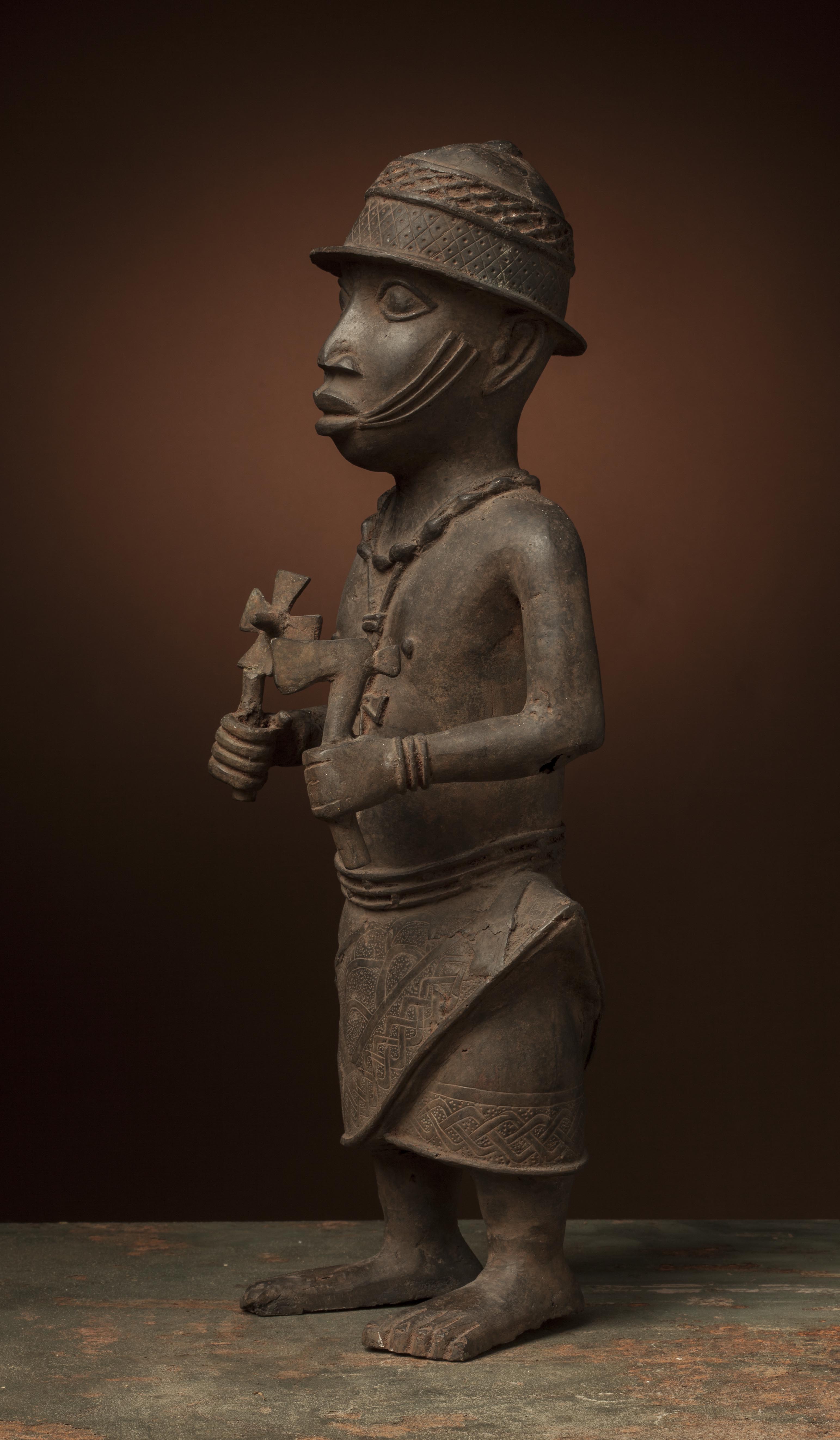 Br.  Bénin (statue), d`afrique : Bénin, statuette Br.  Bénin (statue), masque ancien africain Br.  Bénin (statue), art du Bénin - Art Africain, collection privées Belgique. Statue africaine de la tribu des Br.  Bénin (statue), provenant du Bénin, 63O/75.Statue en bronze.dignitaire portant un casque,un collier et un pendentif avec croix autour du cou,portant dans la main gauche une hache et dans la droite la même croix qu
